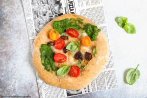 Pizza con mozzarella, pesto di rucola e pomodori